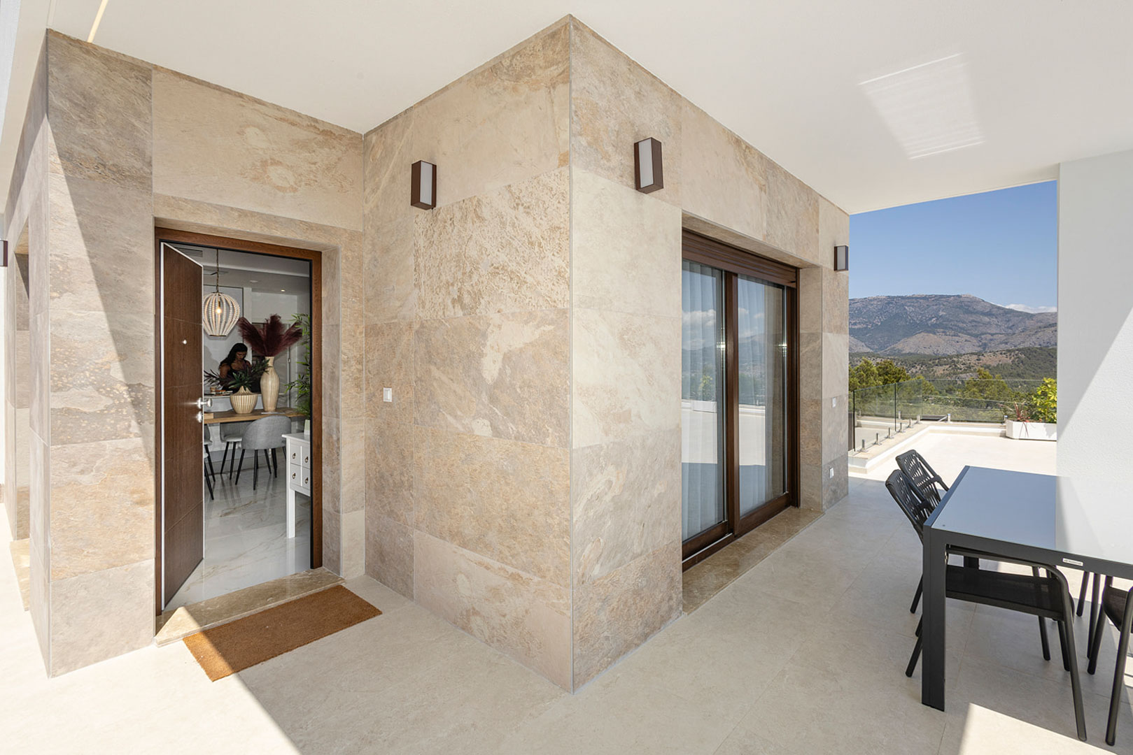 Exterior terrace featuring natural stone cladding, an outdoor dining area, and mountain views. The entrance door leads directly to the interior dining space.