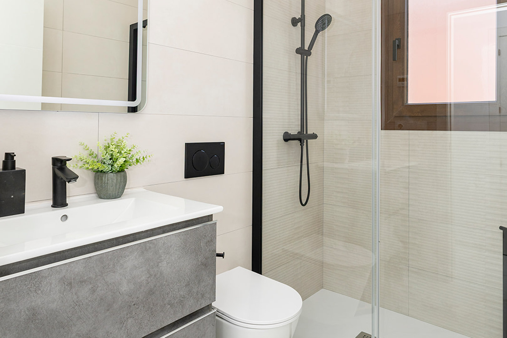 Modern bathroom featuring a grey vanity, matte black fixtures, a wall-hung toilet, and a glass-enclosed shower with textured linear tiles.