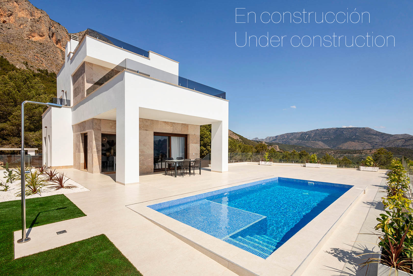 Modern villa exterior featuring a private mosaic pool, porcelain tile terrace, and stone-clad facade overlooking a panoramic mountain landscape.