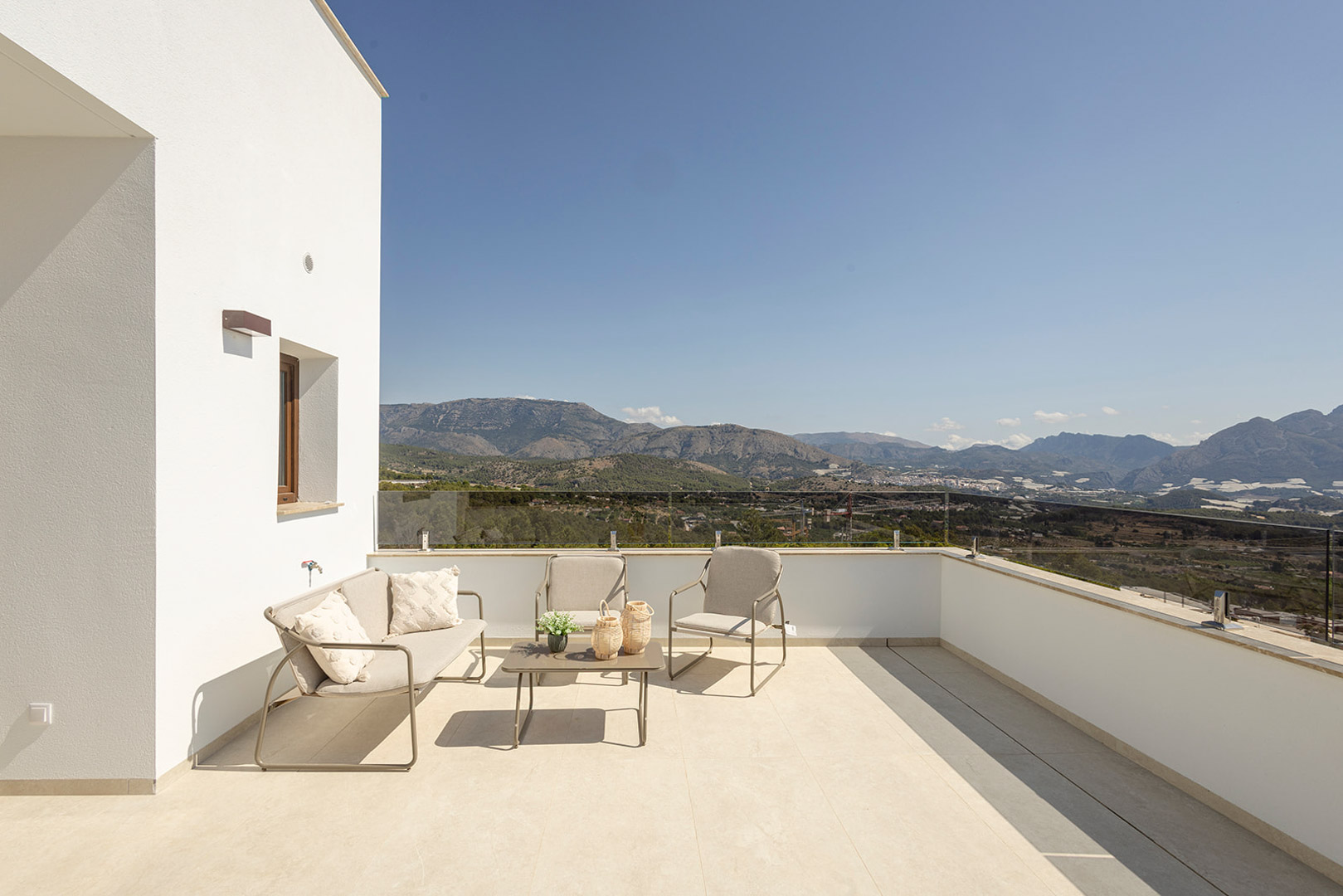 Upper terrace featuring a glass railing and outdoor lounge area, providing panoramic unobstructed views of the mountains and surrounding landscape.