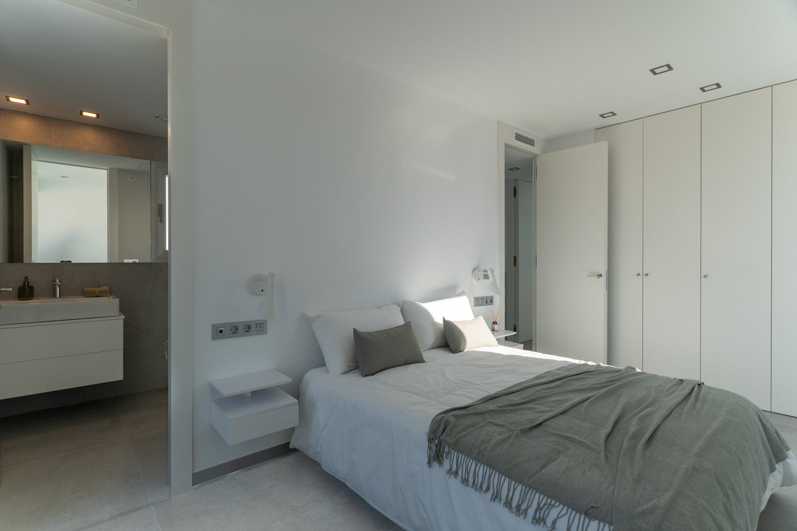 Master bedroom featuring an en-suite bathroom, floor-to-ceiling built-in wardrobes, and a minimalist design with integrated recessed lighting.