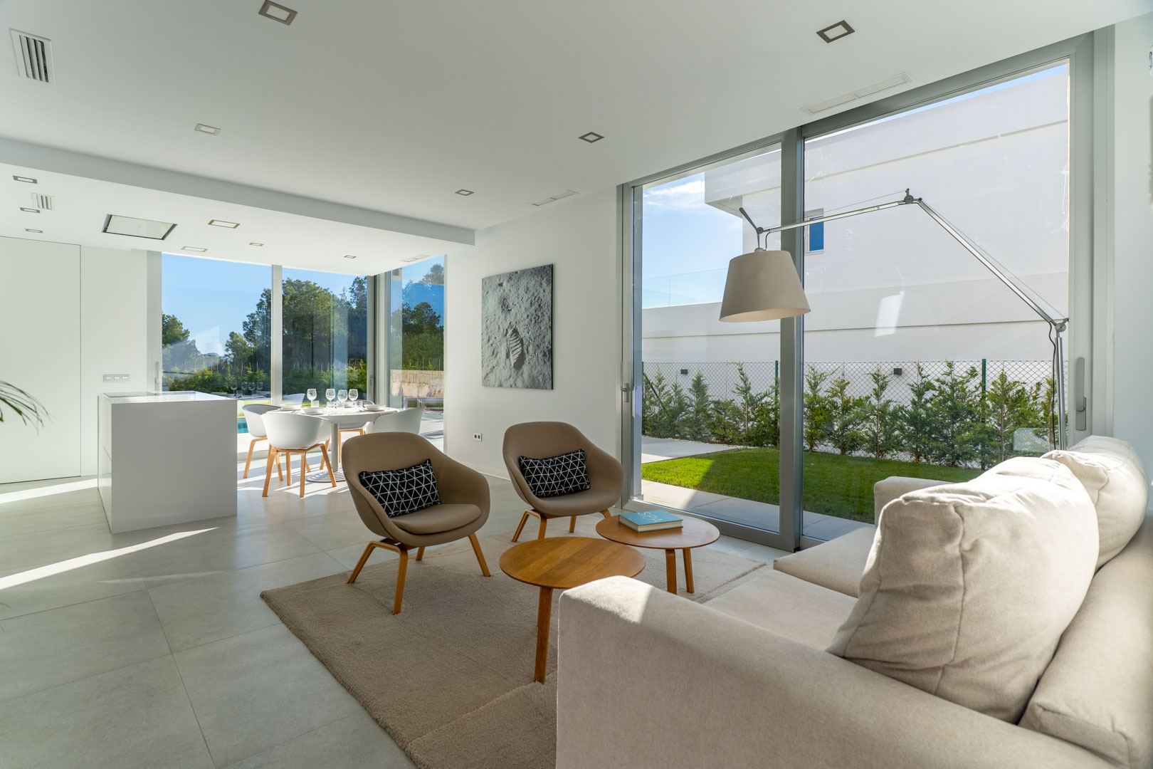 Open-plan living area featuring floor-to-ceiling glass doors, minimalist decor, and recessed lighting that connects seamlessly to the private garden.