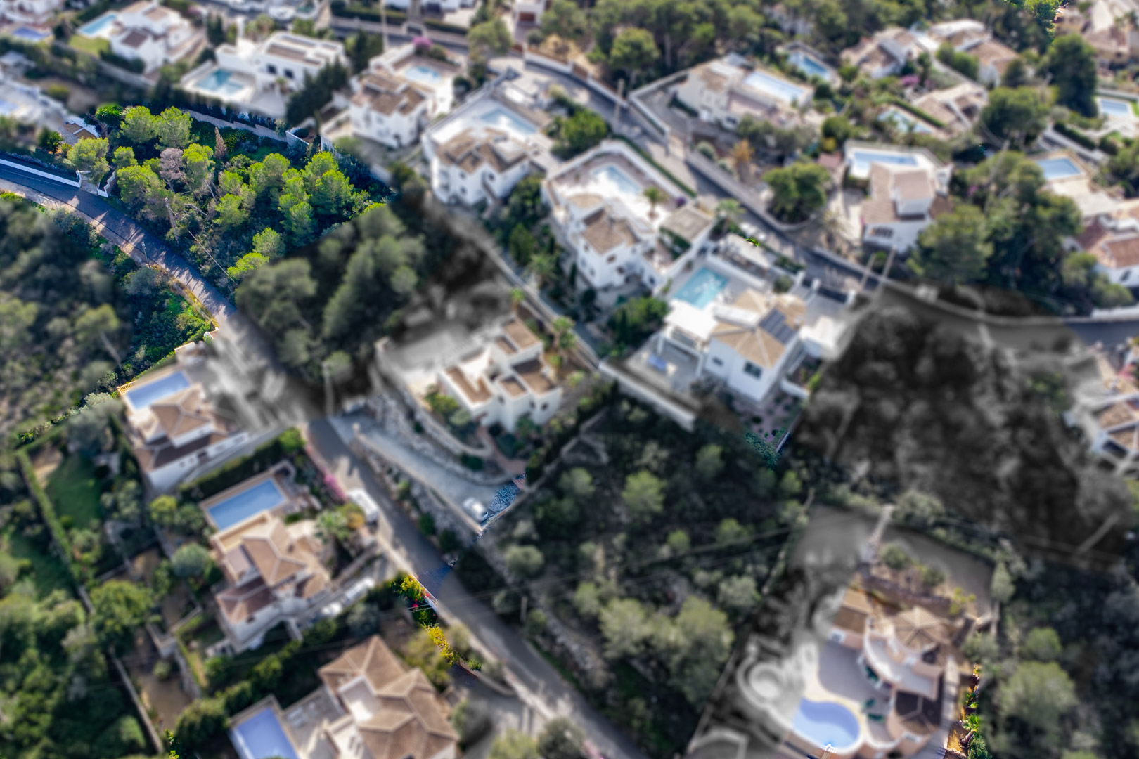 Aerial view of the 1,521 m2 sloped plot featuring Mediterranean pine trees, located within an established residential neighborhood in Granadella-Ambolo.