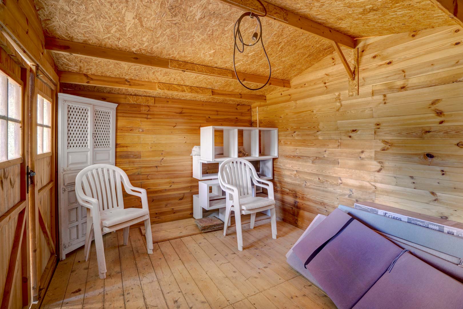 Detached wooden garden shed featuring paneled walls, OSB ceiling, and plank flooring, providing versatile extra storage or hobby space.