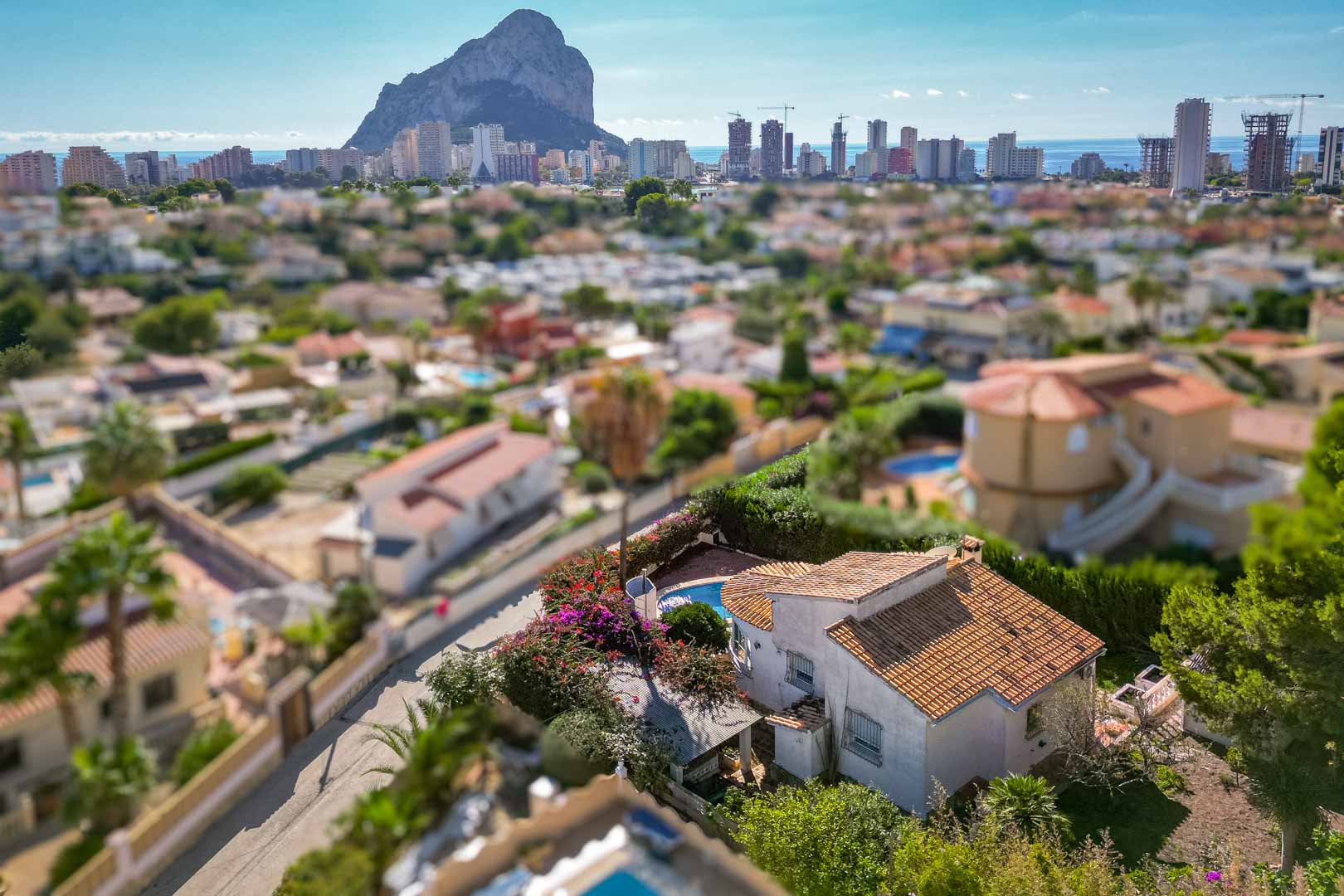 Elevated view of the villa featuring a private pool and garden, offering a clear panoramic vista of the Peñón de Ifach and the Calpe skyline.