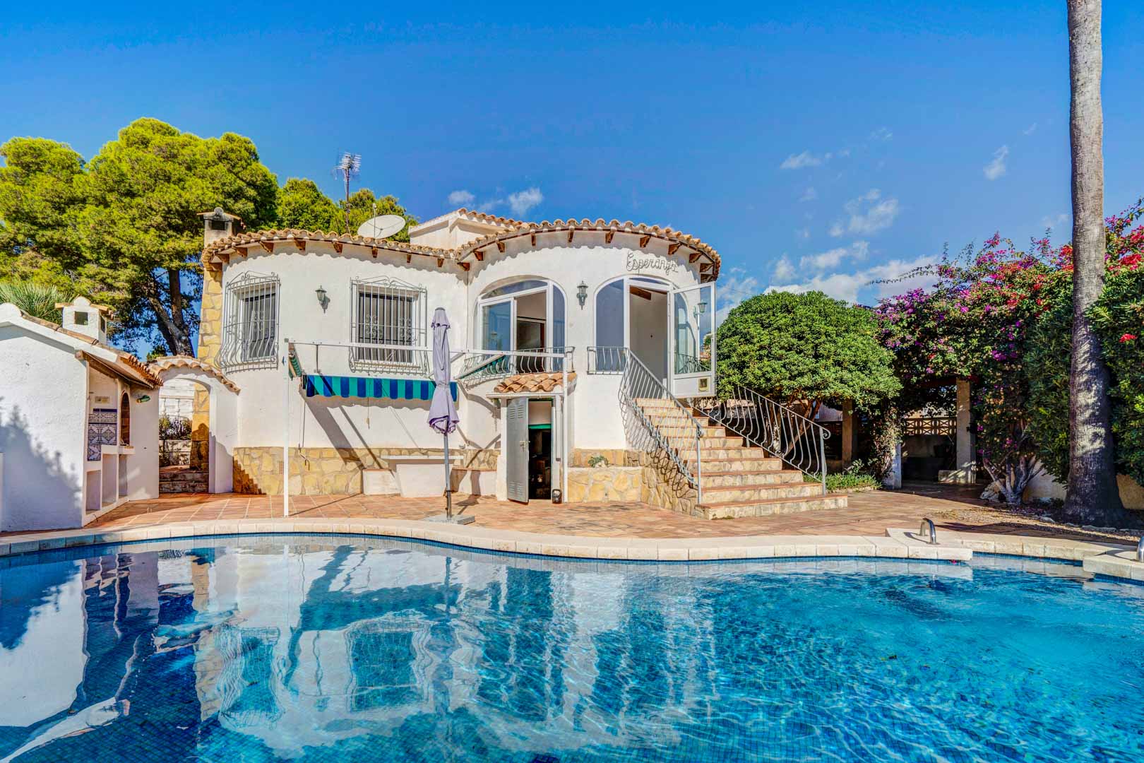 Exterior view of the villa featuring a private swimming pool, white curved facade, and stone stairs leading to the elevated glazed terrace area.
