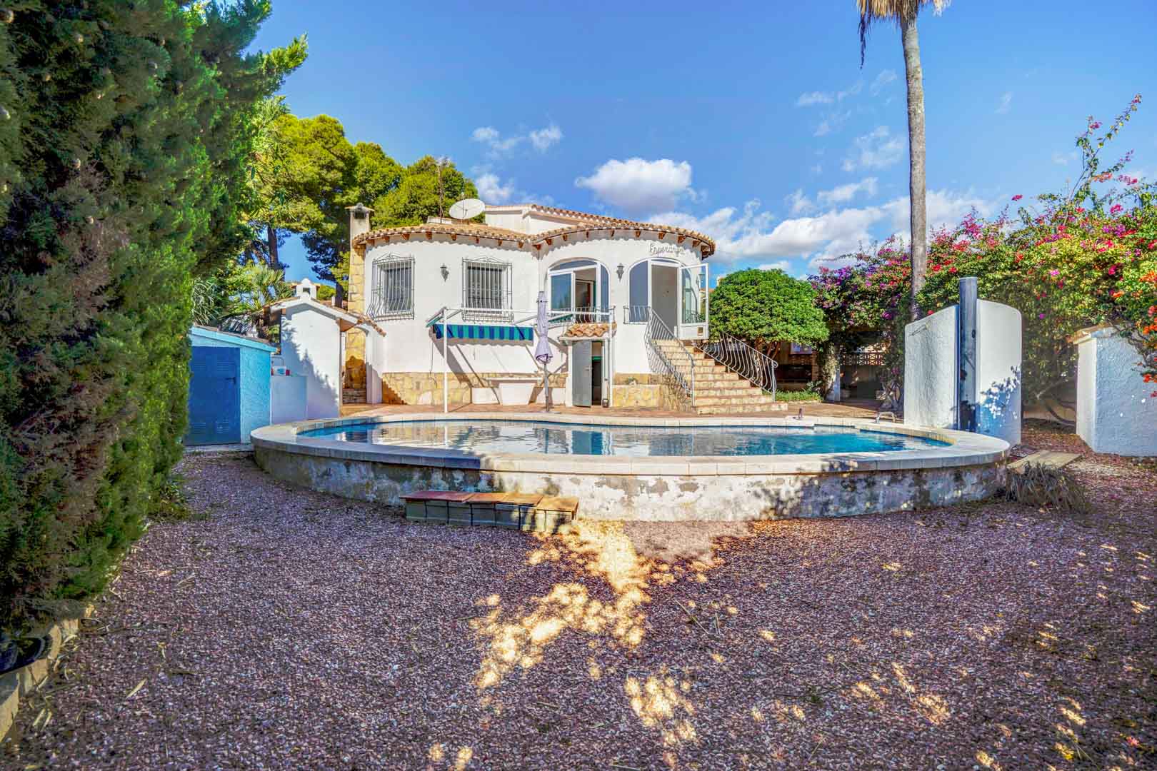 Rear view of the villa featuring a raised private pool, gravel garden, and stone stairs leading to the upper glazed terrace.