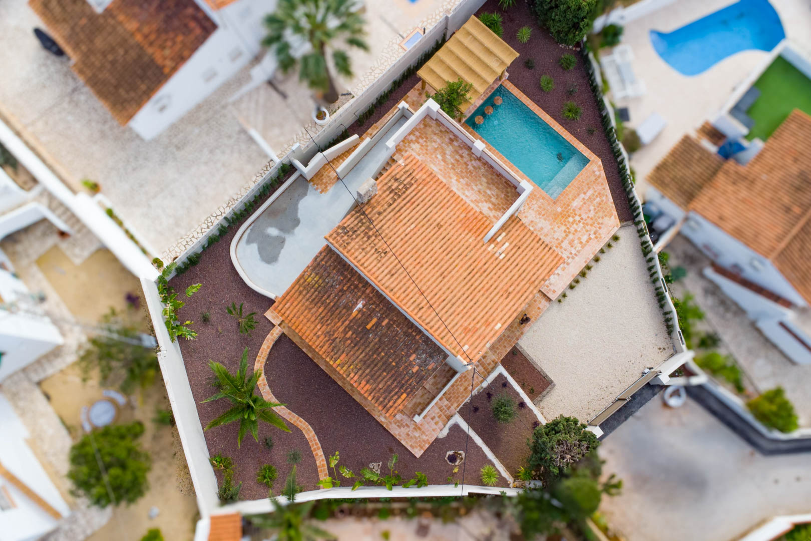 Aerial top-down view of the villa showcasing the plot layout, the swimming pool with integrated seating, terracotta terraces, and landscaped Mediterranean gardens.