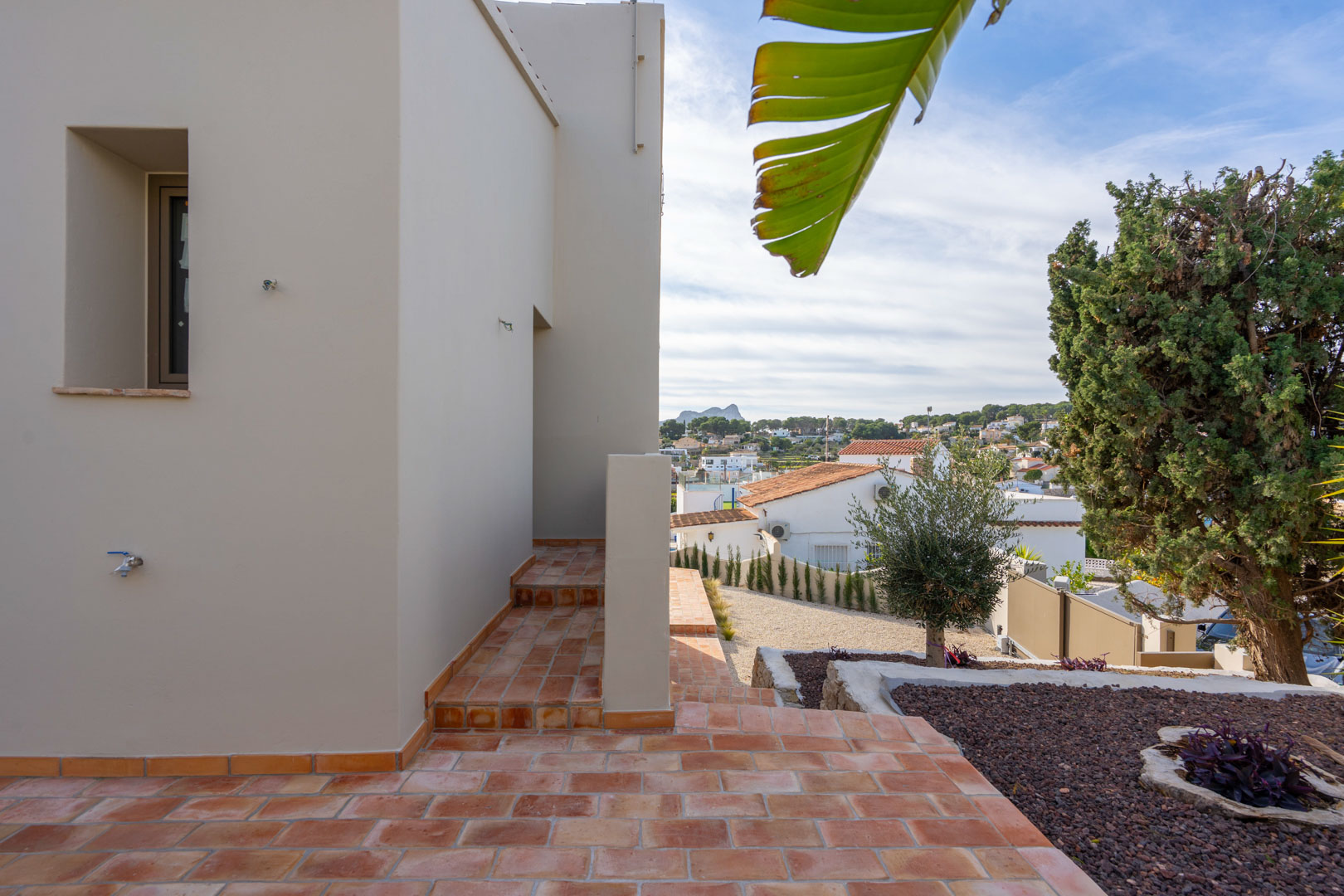 Exterior terrace with terracotta tiles and a landscaped garden, providing clear views of the Peñón de Ifach and the surrounding coastal area.