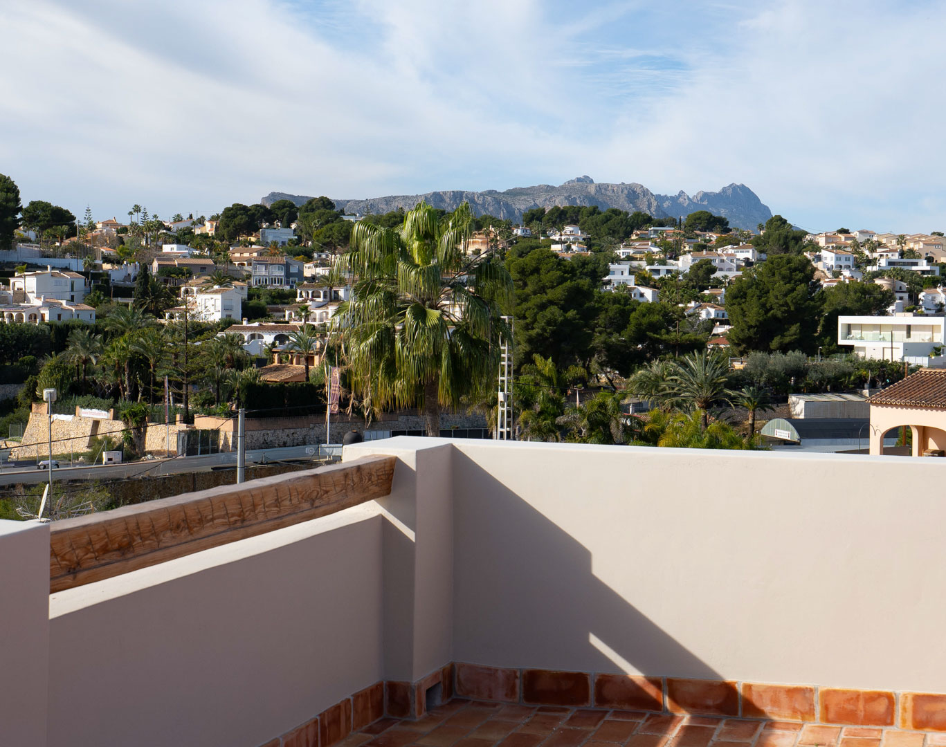 Rooftop terrace featuring traditional terracotta tiling and panoramic views of the Sierra de Bernia mountains and surrounding coastal villas.