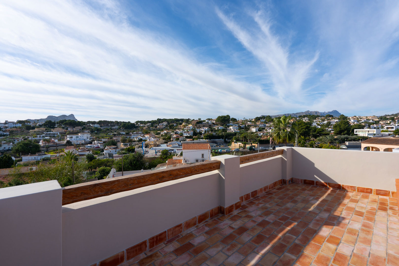 Rooftop terrace featuring traditional terracotta tiling and wooden accents, providing panoramic views of the Peñón de Ifach and the Sierra de Bernia mountains.