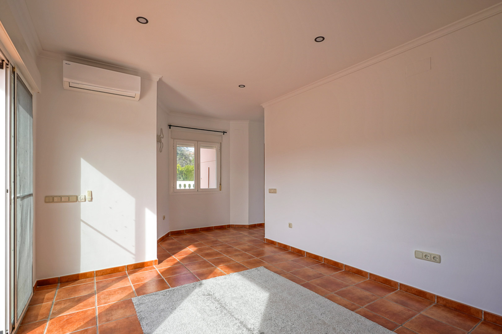 Bright living-dining area featuring rustic terracotta tile flooring, split-system air conditioning, and direct access to the outdoor terrace.