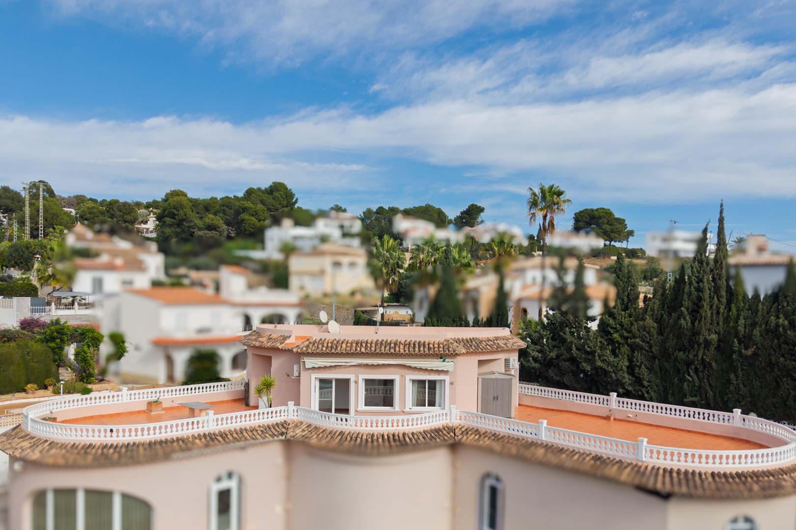 Elevated view of the penthouse showing the expansive wrap-around terrace with terracotta tiling and white balustrades set against a Mediterranean landscape.
