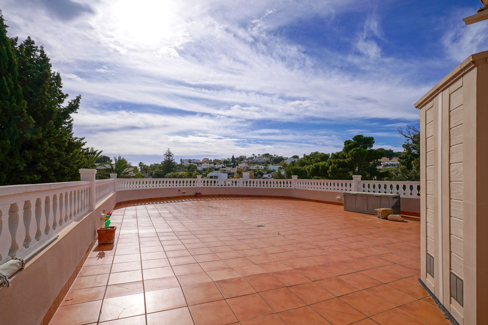 Spacious outdoor terrace featuring terracotta tiling and a white balustrade, providing open views of the surrounding Mediterranean landscape and neighborhood.