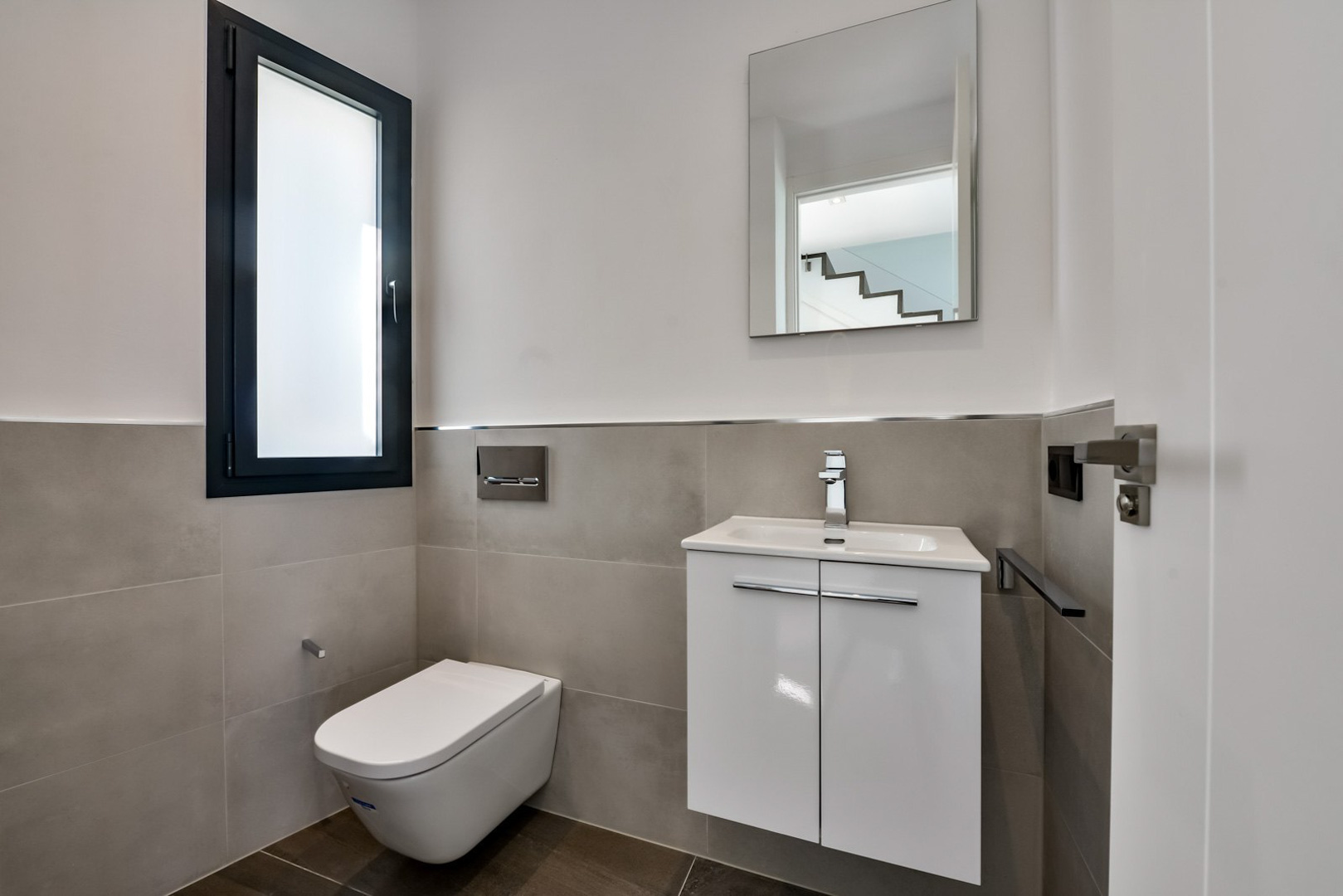Guest toilet featuring a wall-hung toilet, a minimalist white vanity unit, and a frosted glass window with a dark frame.
