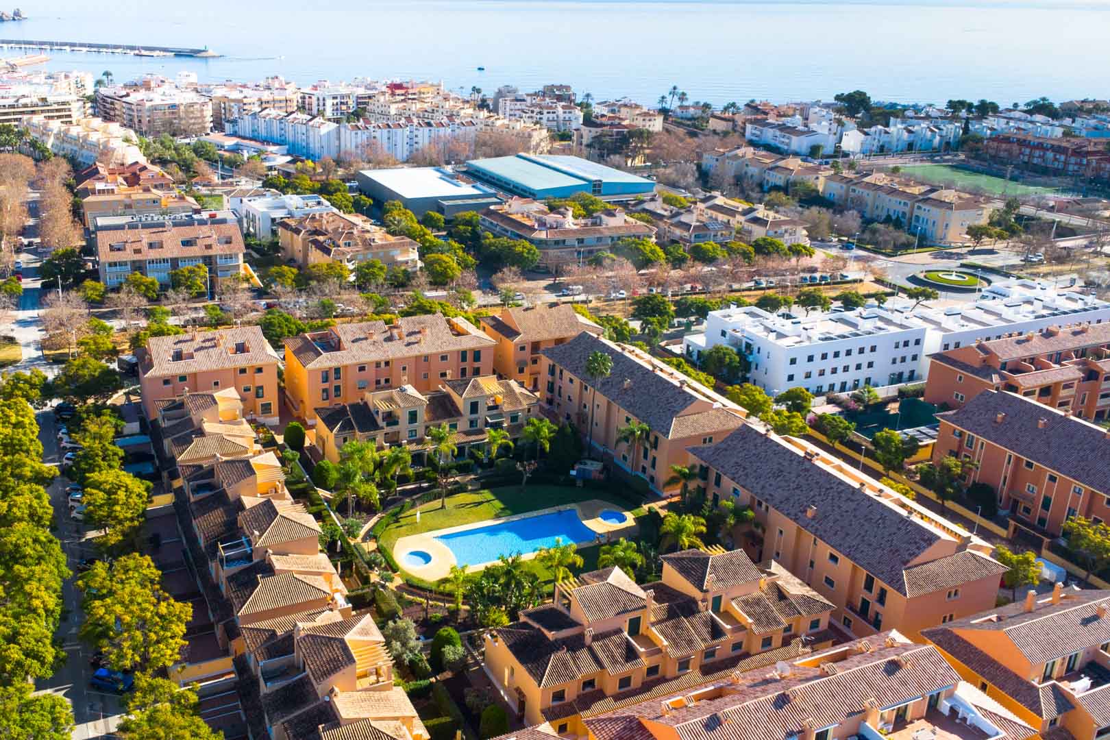 Aerial perspective of the Floridamar residential complex in Jávea, highlighting the central swimming pool, manicured lawns, and Mediterranean sea views.