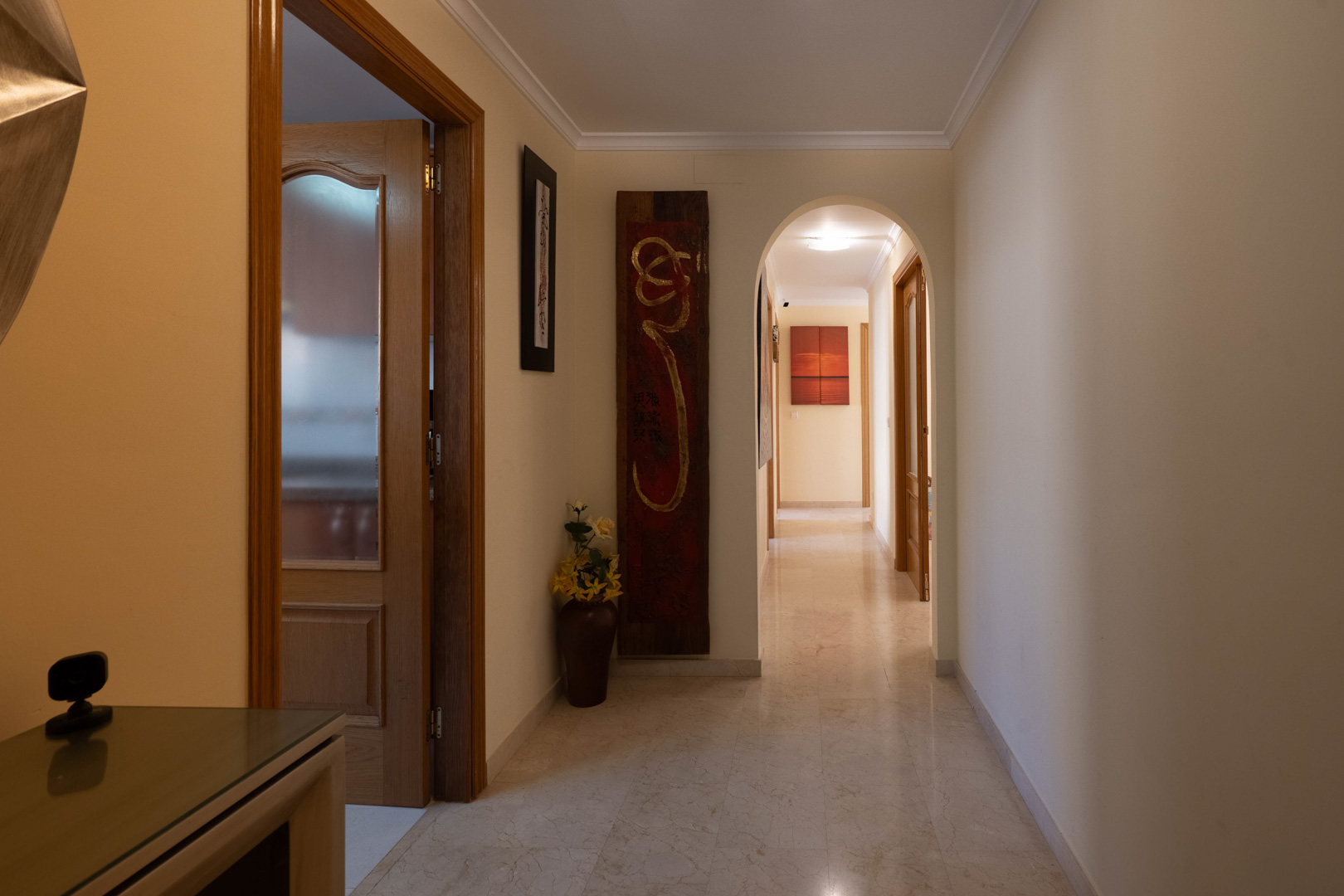 Distribution hallway featuring polished marble flooring, decorative crown molding, and an elegant archway leading to the bedrooms.