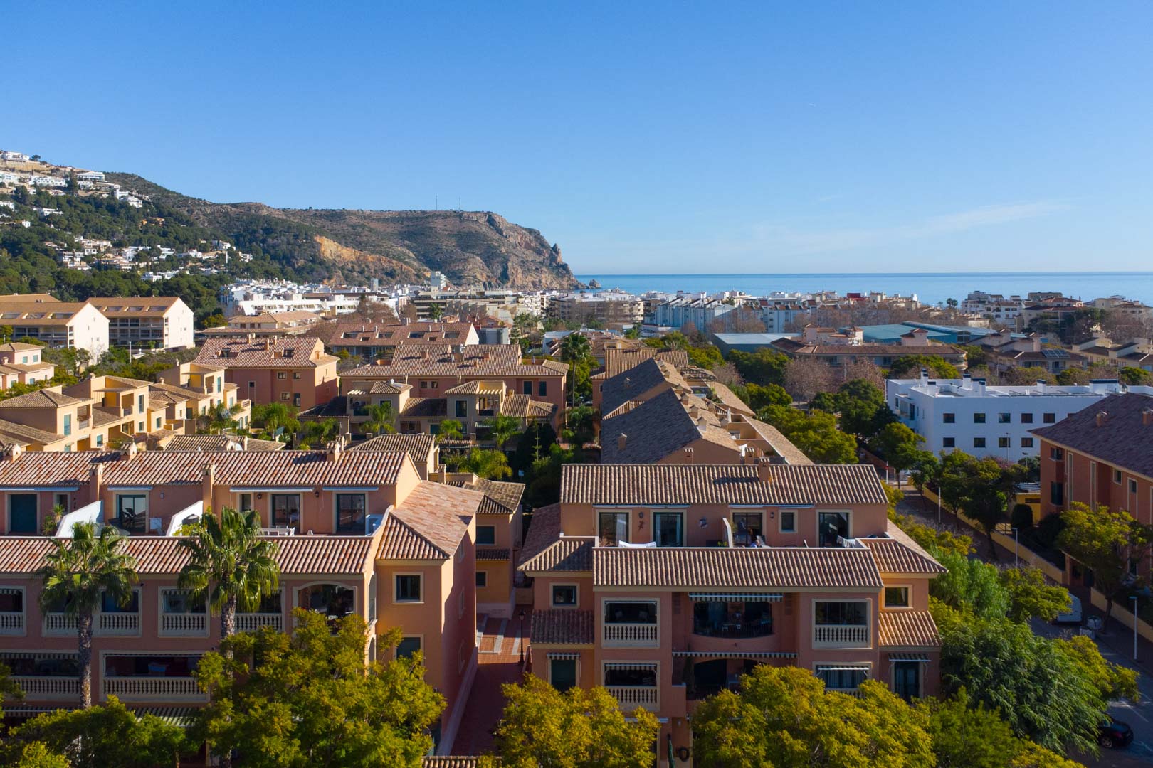 Elevated panoramic view of the Floridamar complex featuring terracotta roofs, Mediterranean Sea views, and the Cabo de San Antonio headland in the background.