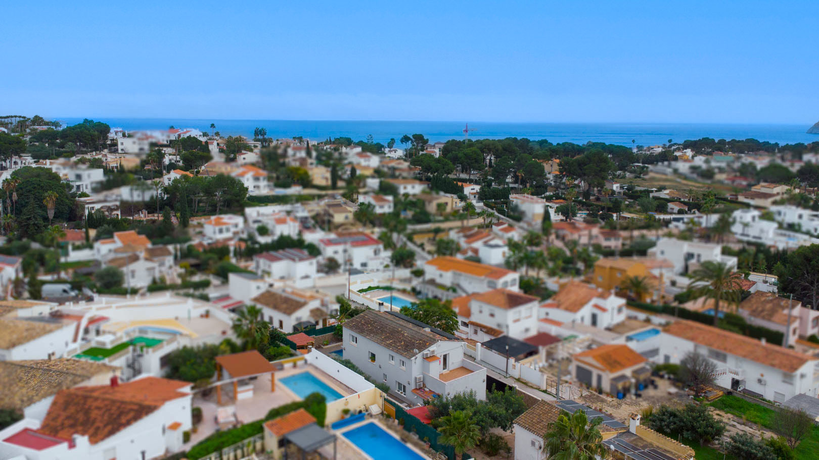 Aerial view of the Carrio urbanization in Calpe, highlighting the proximity to the Mediterranean Sea and the layout of villas with private pools.