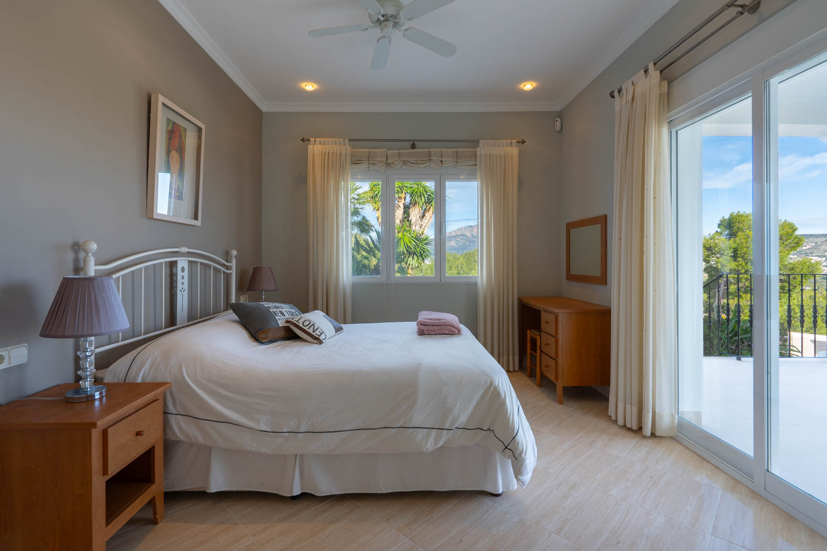 Bright bedroom featuring tiled floors, wooden furniture, and direct terrace access through sliding glass doors with views of the Montgó mountain.