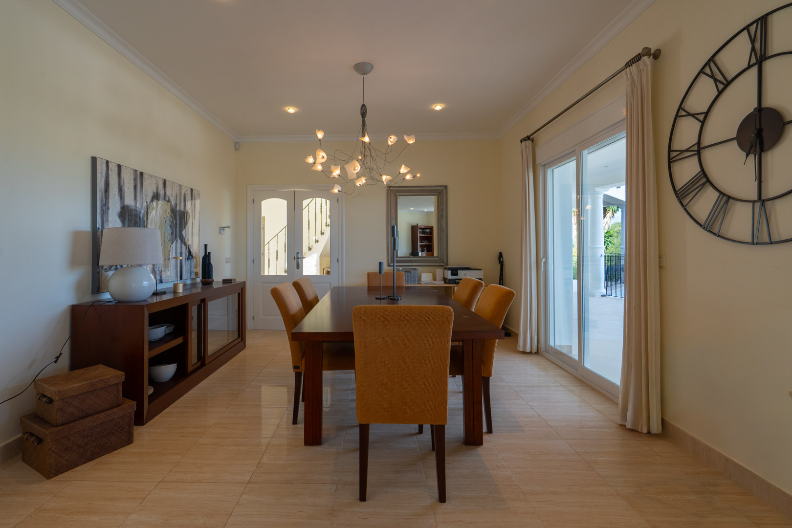 Elegant dining room featuring a solid wood table, mustard upholstered chairs, and direct terrace access through large sliding glass doors.