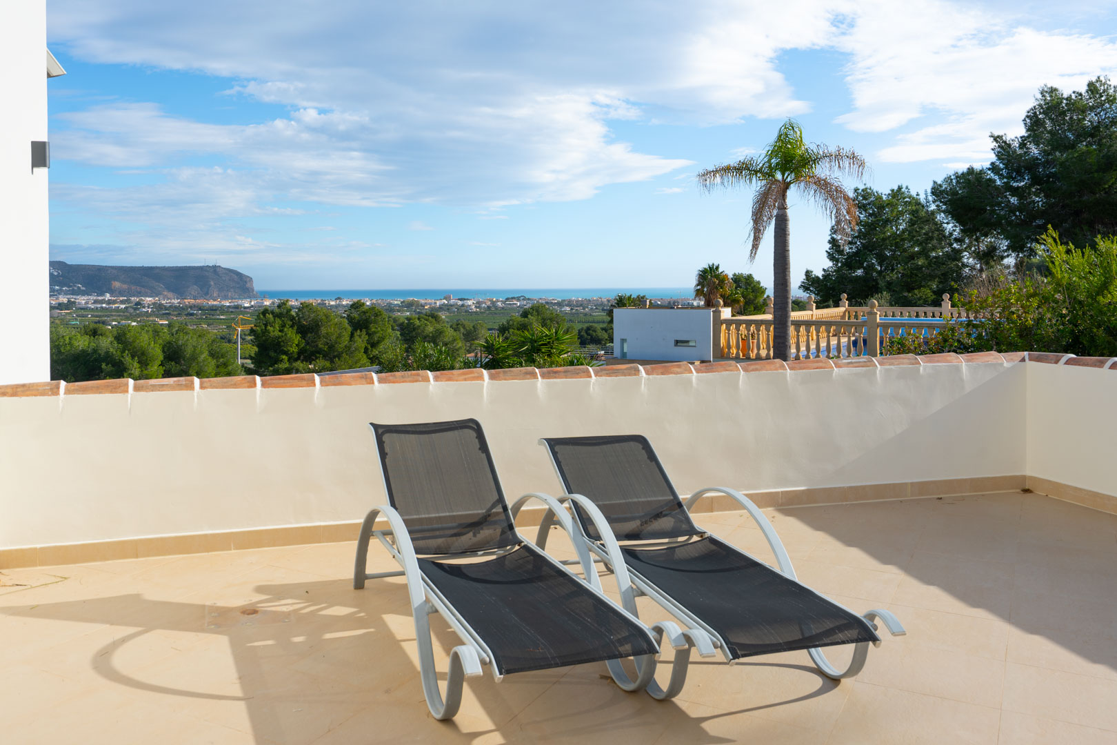 Elevated sun terrace featuring two contemporary loungers and panoramic views of the Mediterranean coastline and the Montgó mountain.