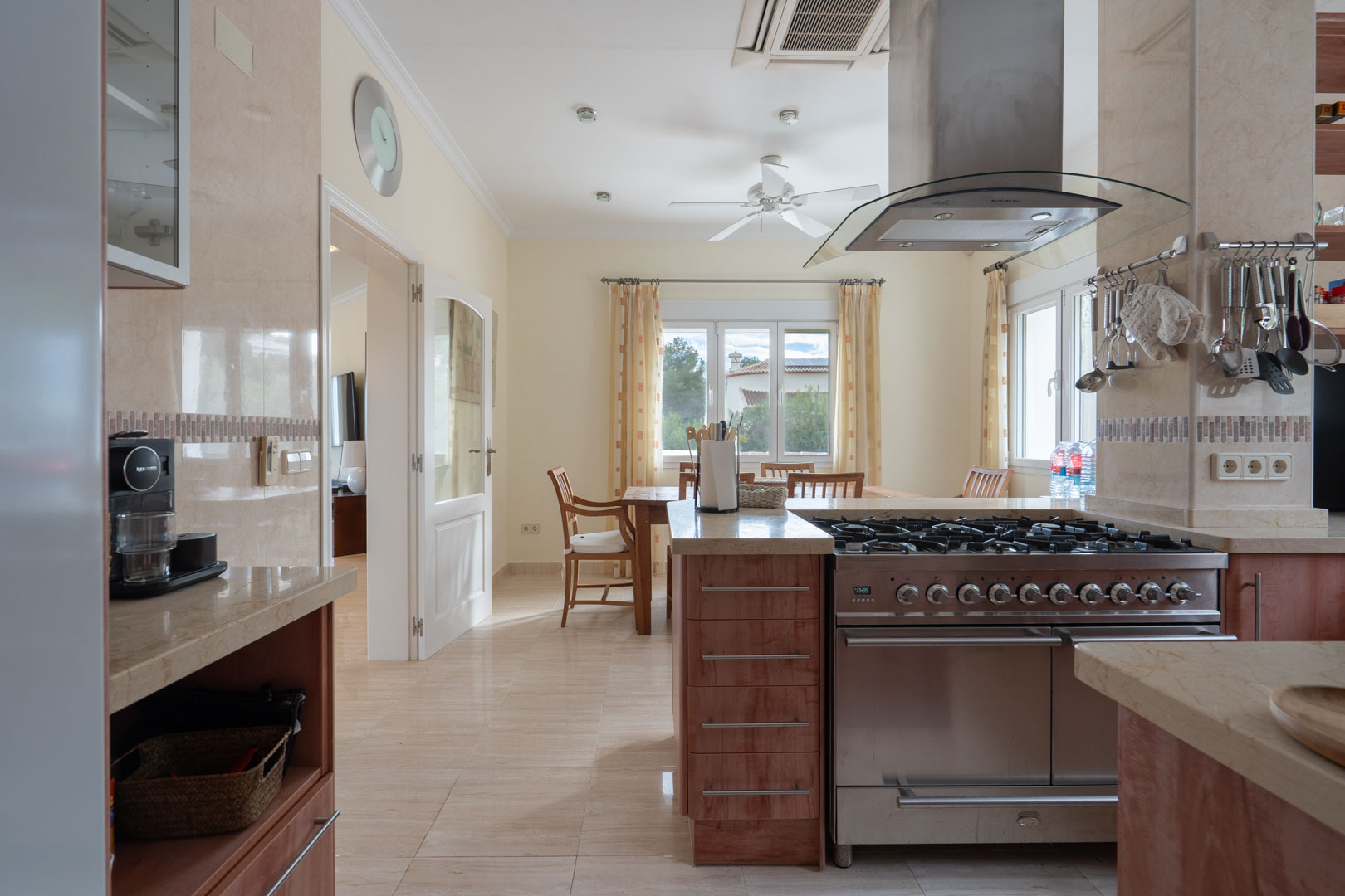 Fully equipped kitchen featuring stone countertops, a professional stainless steel gas range, and an integrated dining area with natural light.