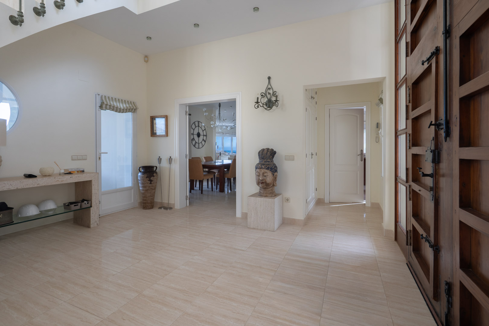 Grand entrance hall featuring polished marble flooring, high ceilings with recessed lighting, and a solid wood door with traditional iron hardware.