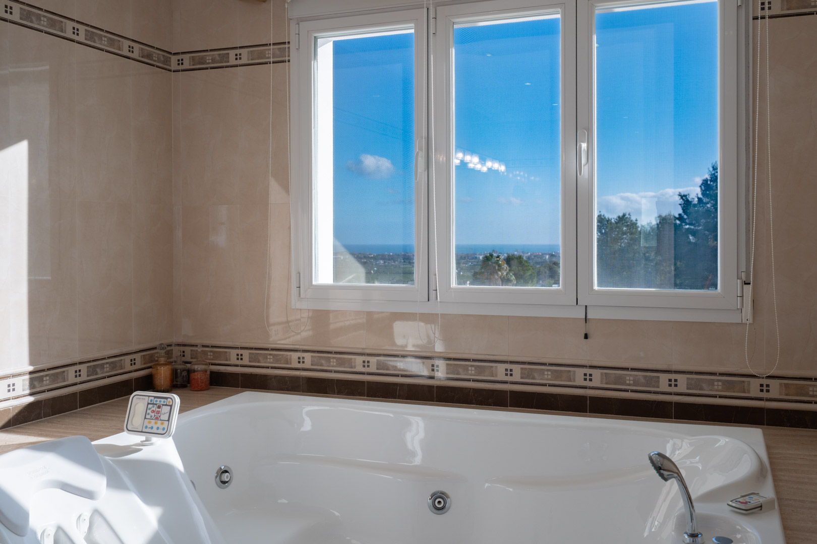 Integrated whirlpool bathtub with digital controls, featuring large windows that provide natural light and panoramic views of the Mediterranean Sea.