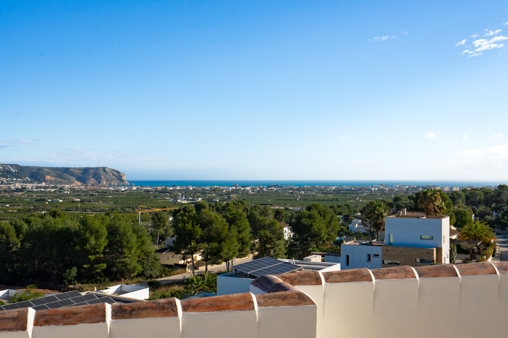 Panoramic views from the upper terrace overlooking the Mediterranean Sea and coastline, featuring the distant headland and local Mediterranean vegetation.