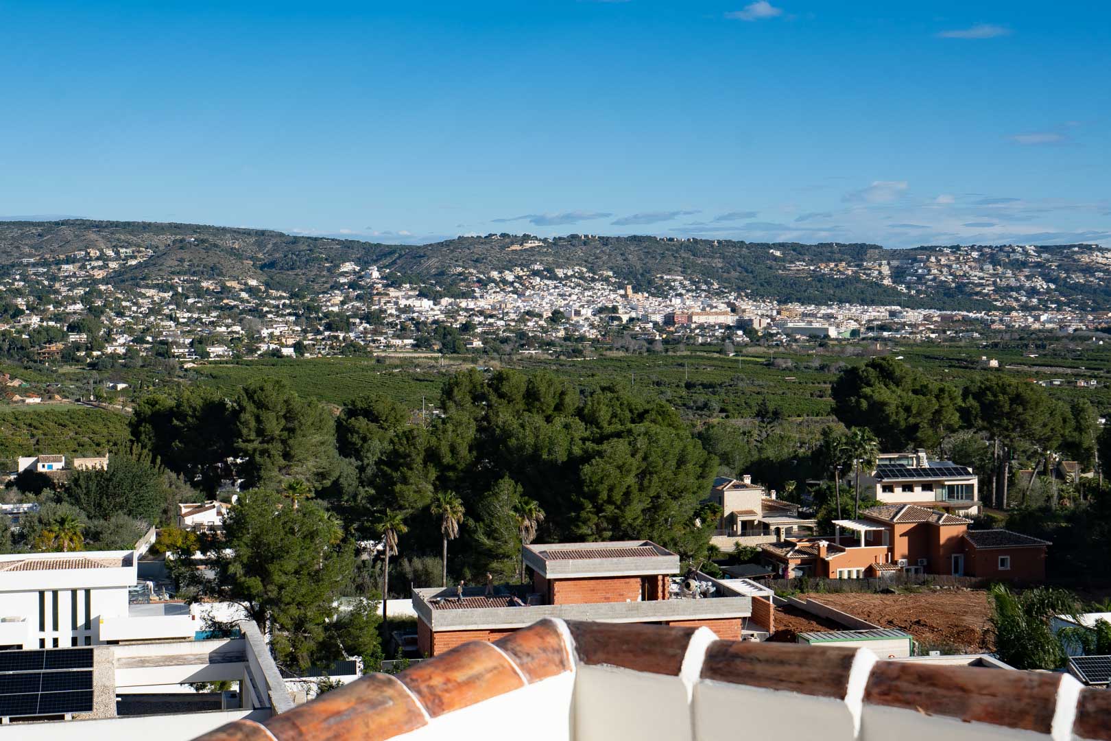 Panoramic views from the upper terrace overlooking the valley and surrounding hills, showcasing the Mediterranean landscape and established residential neighborhood.