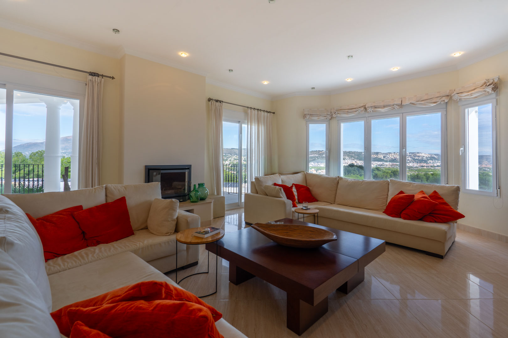 Spacious living room featuring a modern fireplace, polished stone floors, and large windows with panoramic views of the Montgó and the valley.