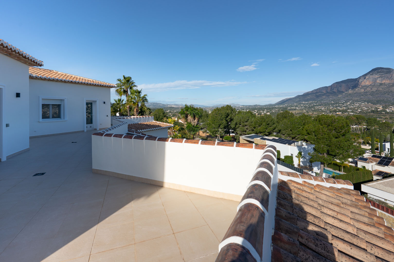 Upper terrace featuring sand-toned ceramic tiling and panoramic views of the Montgó mountain range and the surrounding valley.