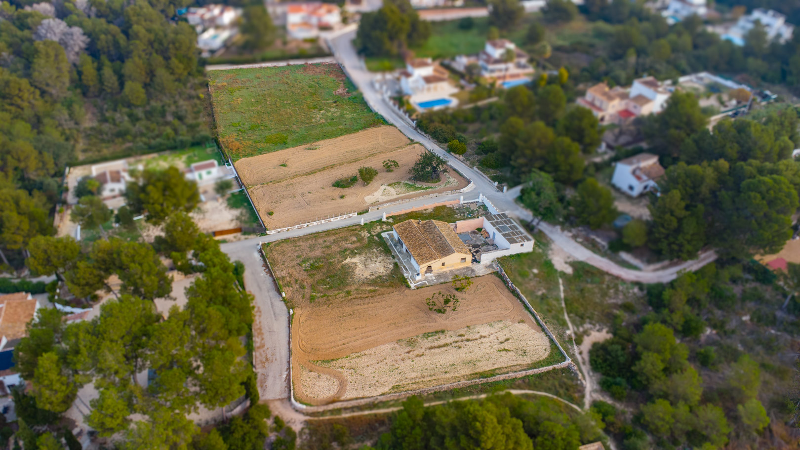 Aerial view showcasing the traditional finca and its expansive flat rustic plots, surrounded by Mediterranean vegetation and pine forests in Jávea.