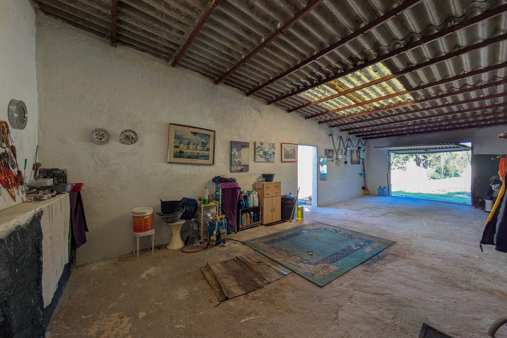 Spacious garage or workshop area featuring concrete flooring, whitewashed walls, and high ceilings with a skylight for natural illumination.
