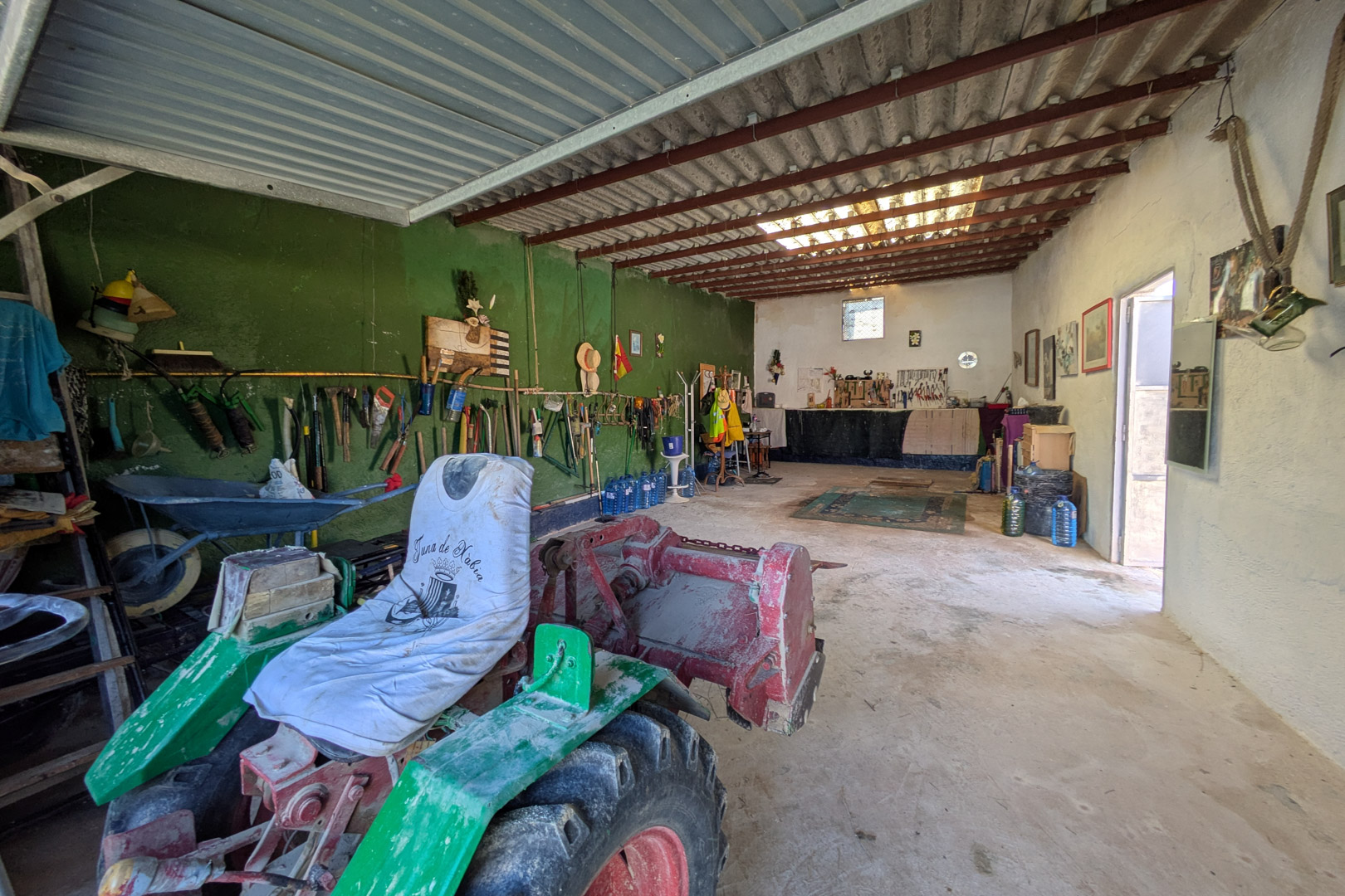 Spacious workshop or storage area featuring concrete flooring and high ceilings with metal beams, suitable for agricultural machinery and maintenance tools.