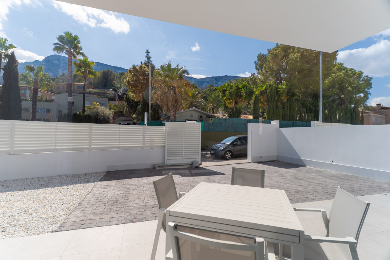 Outdoor terrace featuring a dining area and private parking space. The property offers clear views of the Montgó mountain range within a contemporary architectural setting.