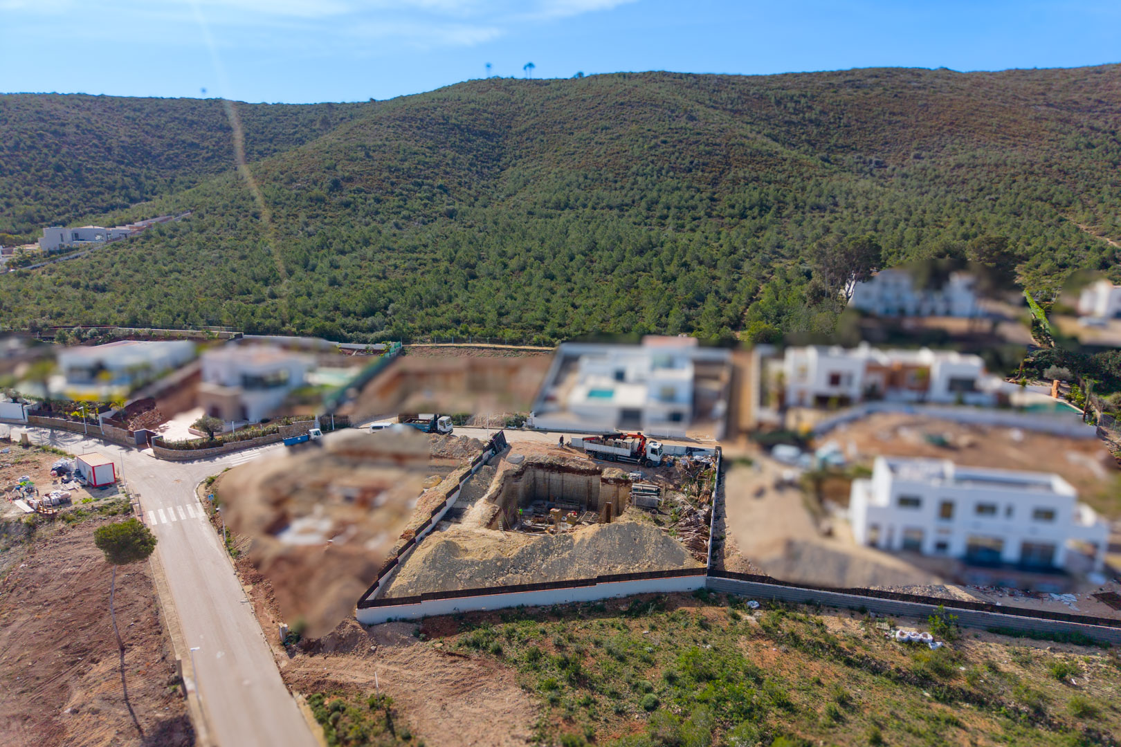 Aerial perspective of the plot during the construction phase, showing the foundation excavation for the basement level within a modern residential area in Jávea.