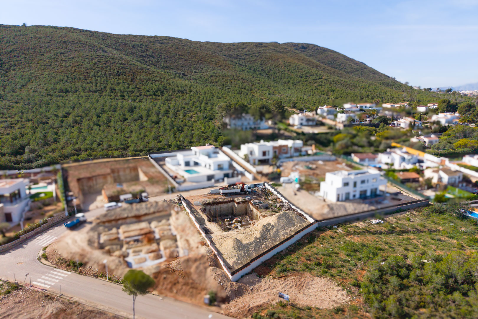 Aerial view of the plot under construction in Valsol, showing the initial excavation and foundation phase surrounded by modern villas and Mediterranean hills.