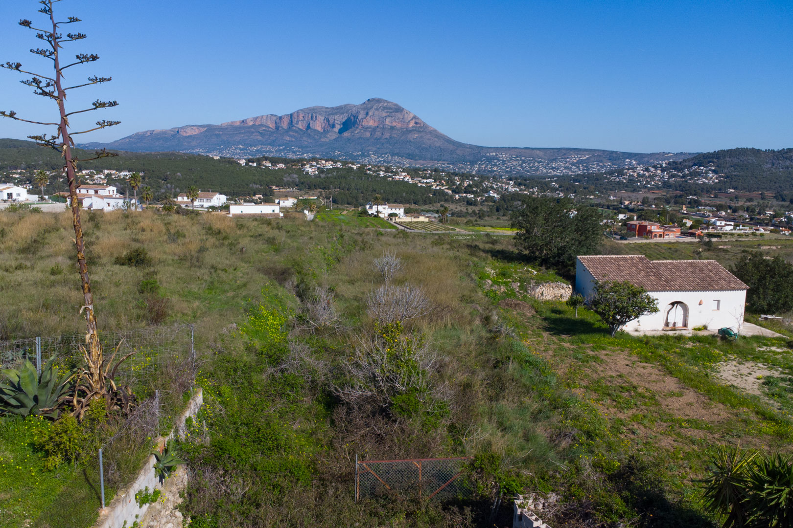 Panoramic view from the rustic plot overlooking the Benitachell valley, featuring the Montgó mountain and natural Mediterranean vegetation.