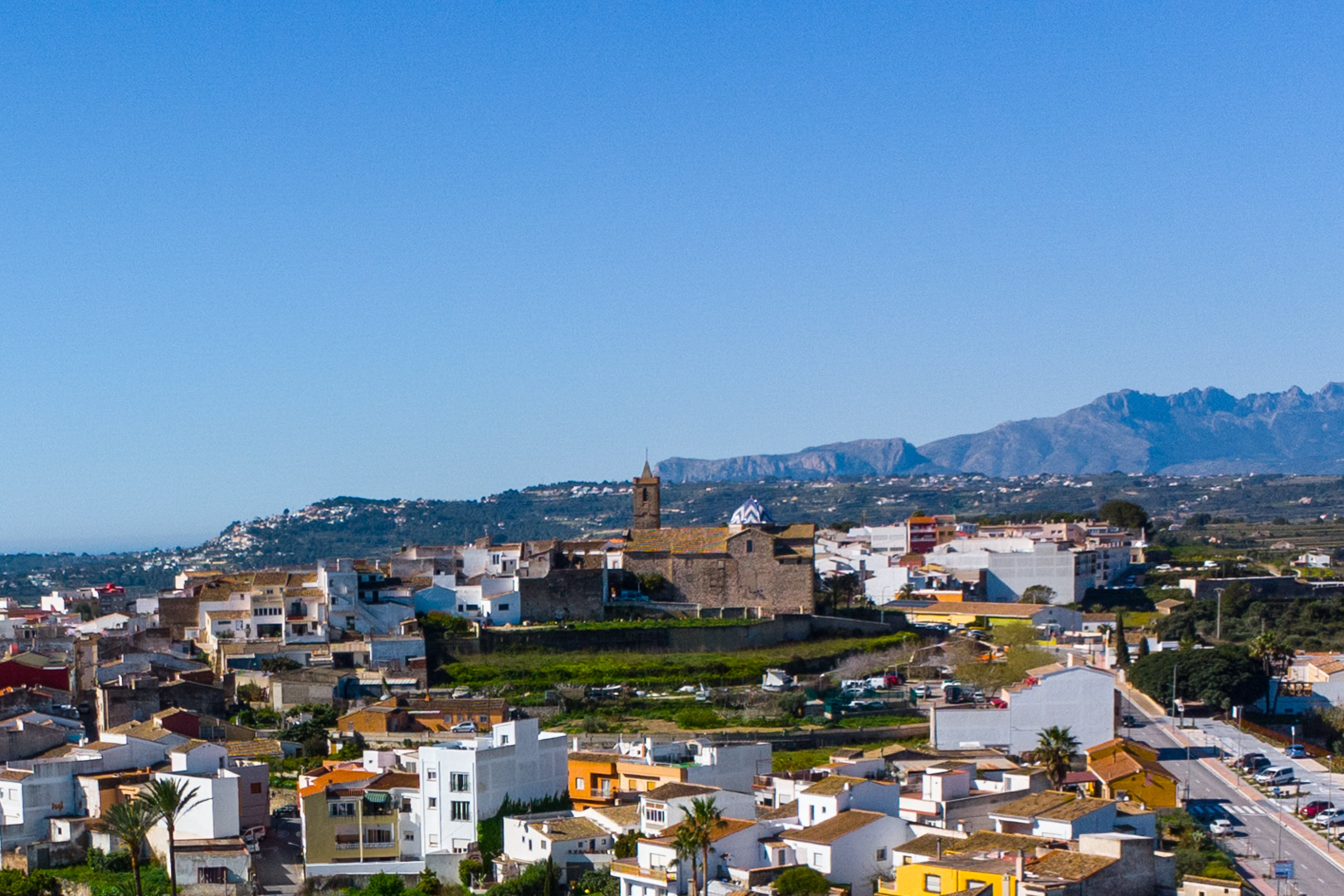 Panoramic view of Benitachell village featuring the blue-domed church and the Montgó mountain range in the background.