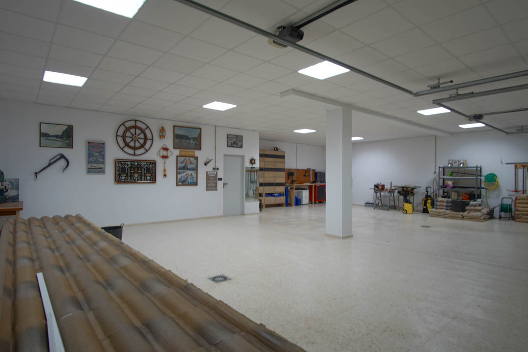 Spacious five-car garage featuring recessed LED lighting, a dedicated workshop area with shelving, and walls adorned with nautical-themed decor.