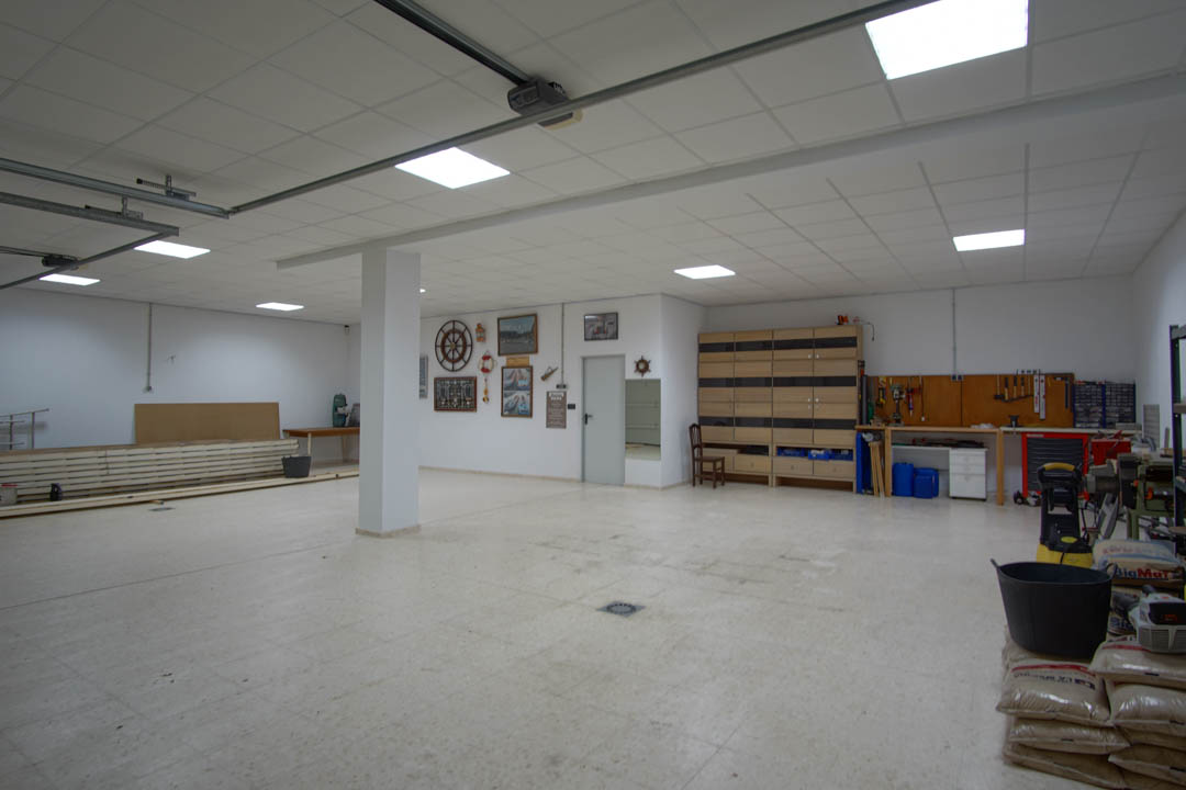 Spacious multi-car garage featuring a dedicated workshop area, integrated storage solutions, and bright LED panel lighting on a modular ceiling.