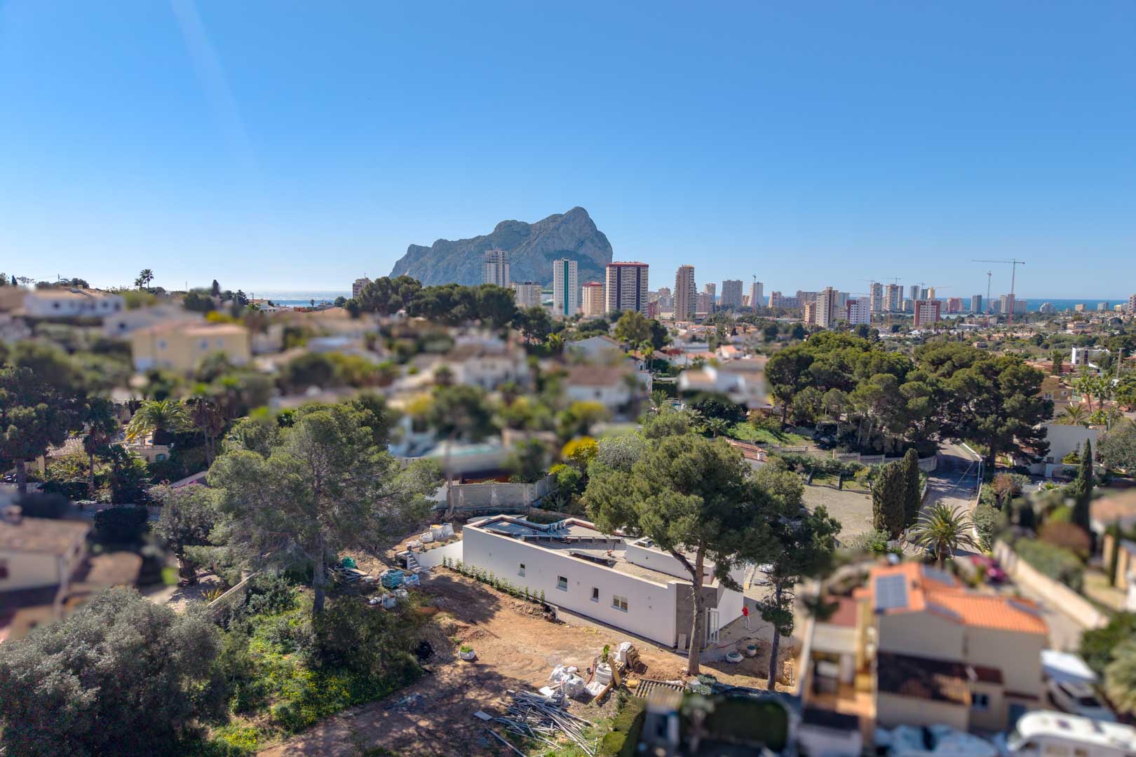 Aerial perspective of the minimalist villa under construction, featuring its single-story layout and strategic views of the Peñón de Ifach and Calpe's coastal skyline.