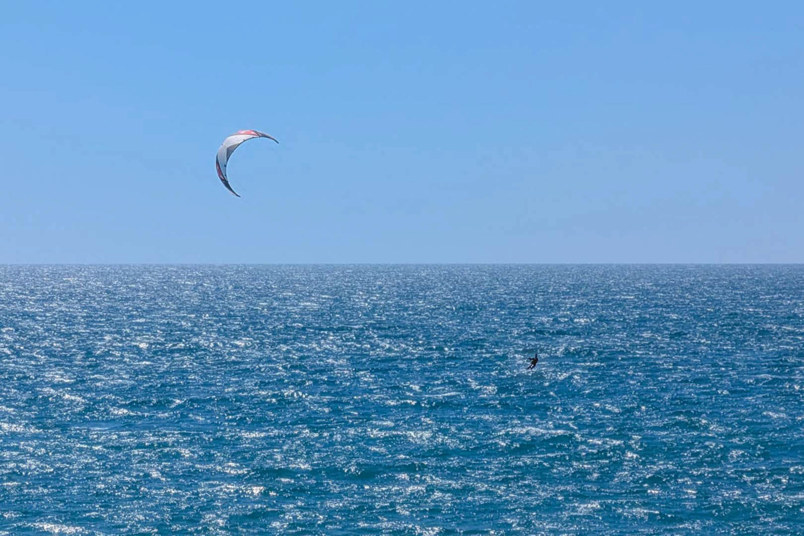 Panoramic view of the Mediterranean Sea near Calpe, featuring a kitesurfer enjoying the coastal breeze under a clear blue sky.