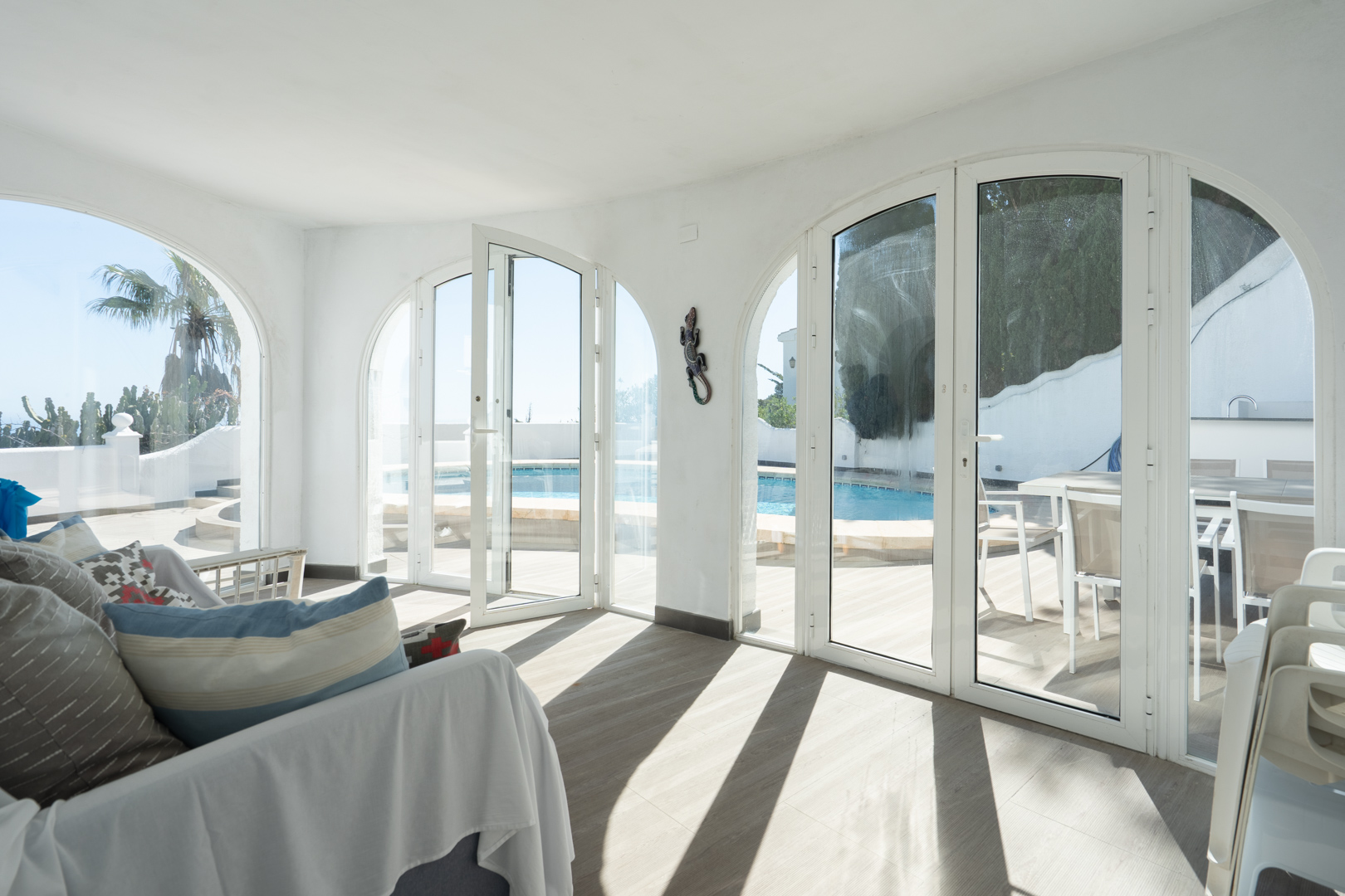 Glazed naya featuring large arched glass doors that provide direct access to the swimming pool terrace and outdoor dining area.