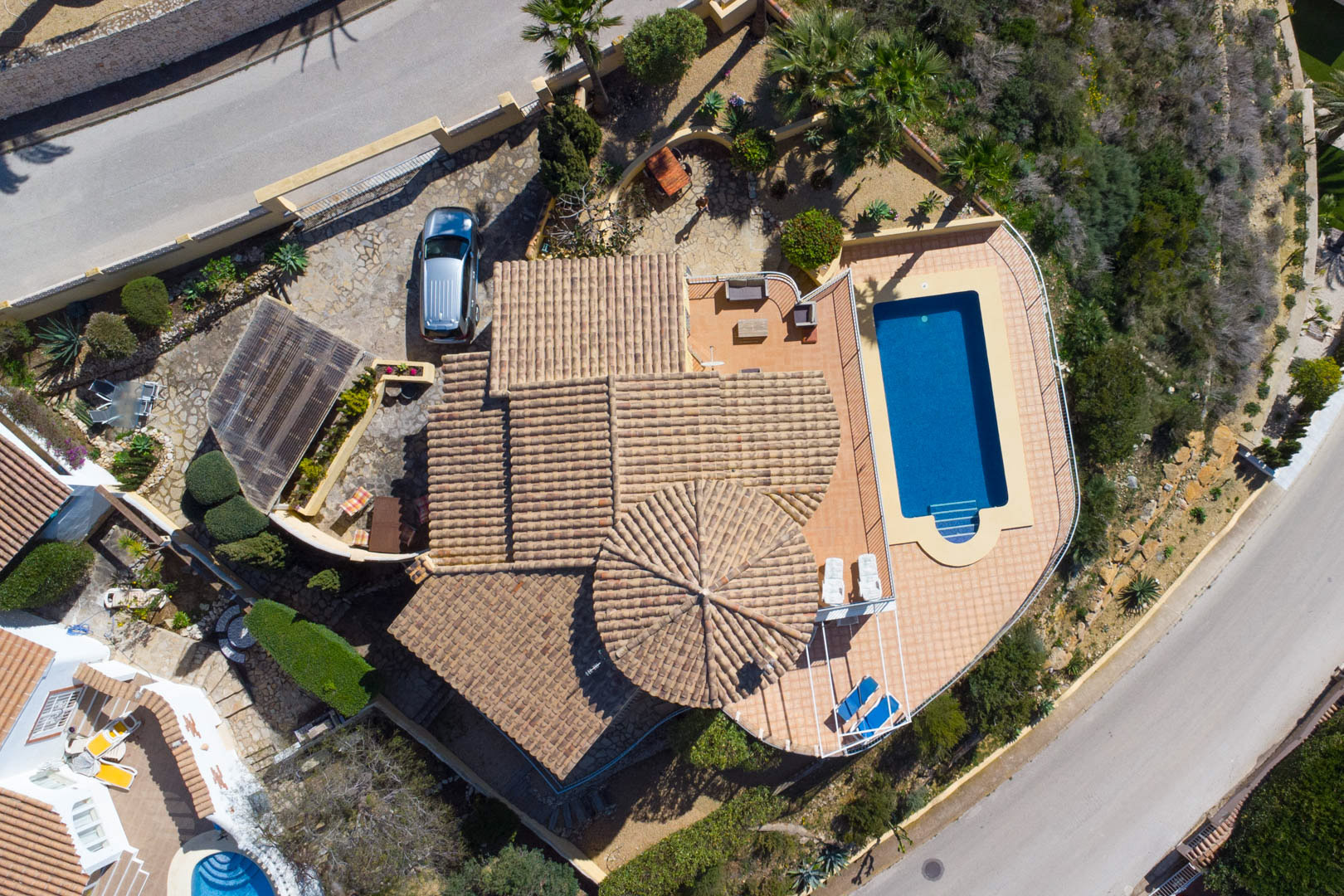 Aerial perspective showing the villa's layout, featuring traditional tiled roofs, a rectangular swimming pool with a sun terrace, and a private driveway with a carport.