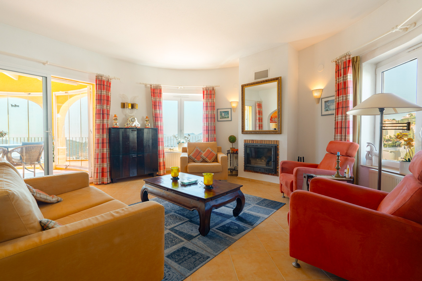Bright living area featuring an inset fireplace, terracotta tile flooring, and direct access to the naya and sun terrace via large sliding doors.