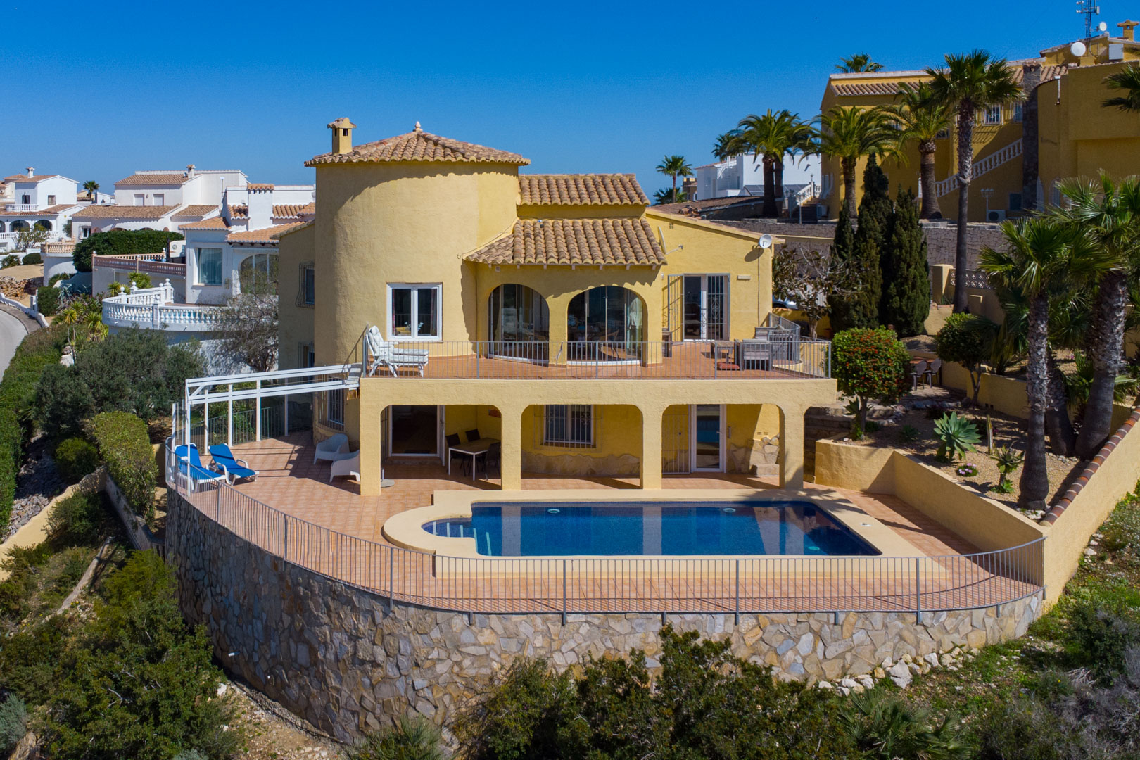 Exterior view of the villa featuring a private swimming pool, multi-level terracotta terraces, and a traditional natural stone masonry retaining wall.