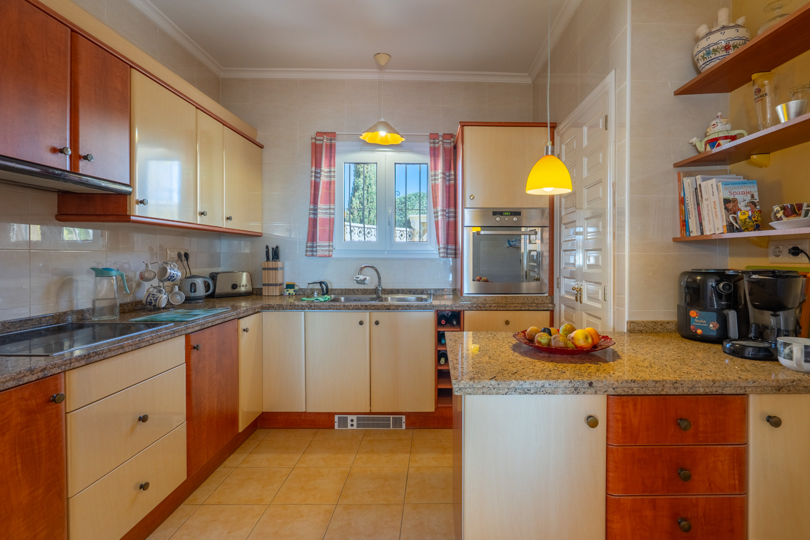 Fully equipped kitchen featuring granite countertops, two-tone wood and cream cabinetry, and integrated appliances. Includes open shelving and a window providing natural light.